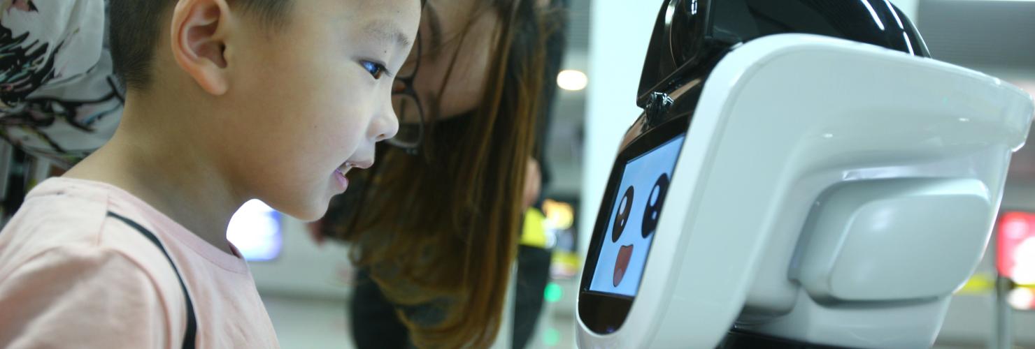 A boy looks at the intelligent robot "Xiaogui" at Yinghua Park metro station in Ningbo, Zhejiang Province.