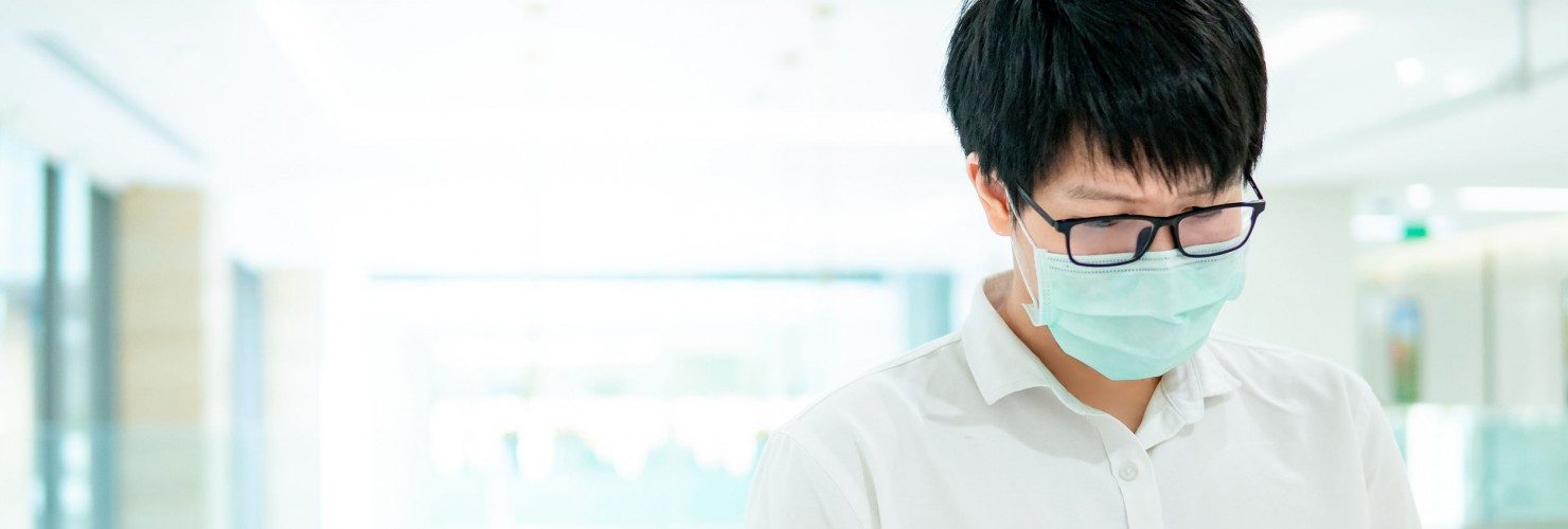 A man wearing a facemask looks at his smartphone