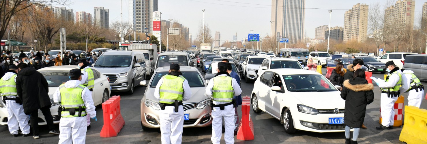 Police officers wearing face masks check drivers' COVID-19 test documentation at an entrance of an expressway