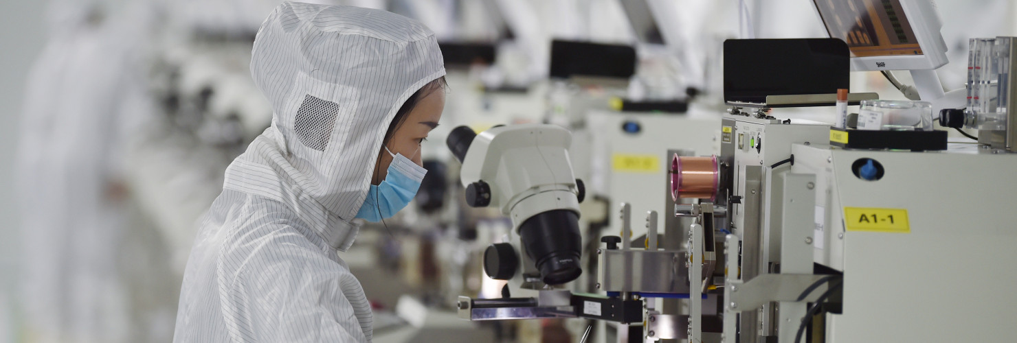 A worker wearing a mask and protective clothing makes chips in a dust-free workshop at a semiconductor company in Suqian, Jiangsu province, China.