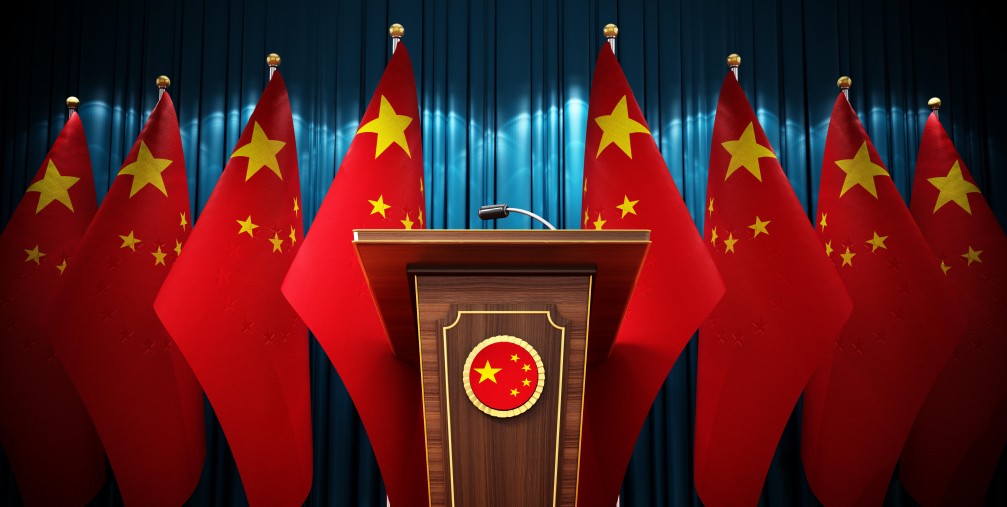 Group of Chinese flags standing next to lectern in the conference hall. 3D illustration. 