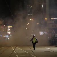 A journalist runs away from tear gas at Lan Kwai Fong, Hong Kong 