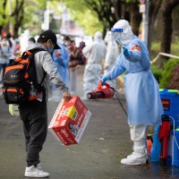 A staff member helps a villager disinfect baggage when he returns to Lianqin Village