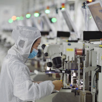 A worker wearing a mask and protective clothing makes chips in a dust-free workshop at a semiconductor company in Suqian, Jiangsu province, China.