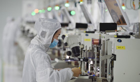 A worker wearing a mask and protective clothing makes chips in a dust-free workshop at a semiconductor company in Suqian, Jiangsu province, China.